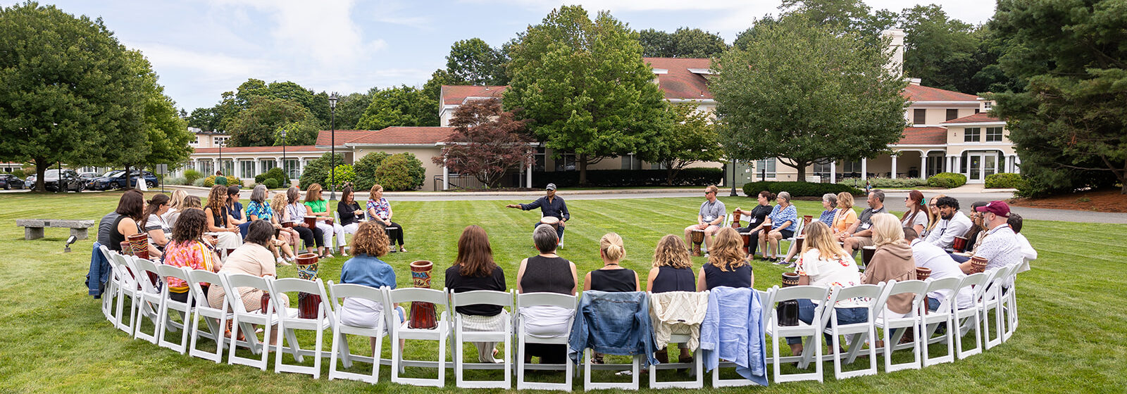 A group of educators sit in a drum circle outdoors